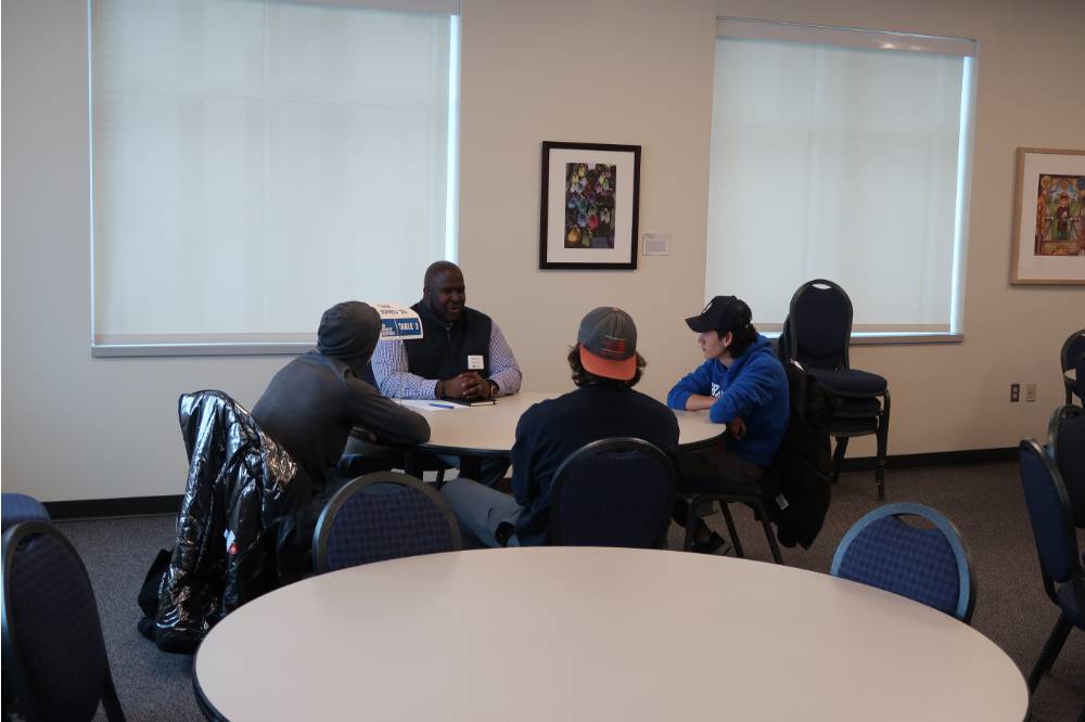 An alumnus talking with three students at the 30 Minute Mentors Event